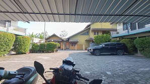 A covered parking area with a motorcycle and a black SUV parked. - Jj House Kost Exclusive Nologaten (Depok)