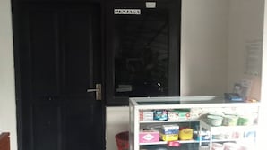 A closed black door with a sign above it and a glass display case with various products. - Jj House Kost Exclusive Nologaten (Depok)