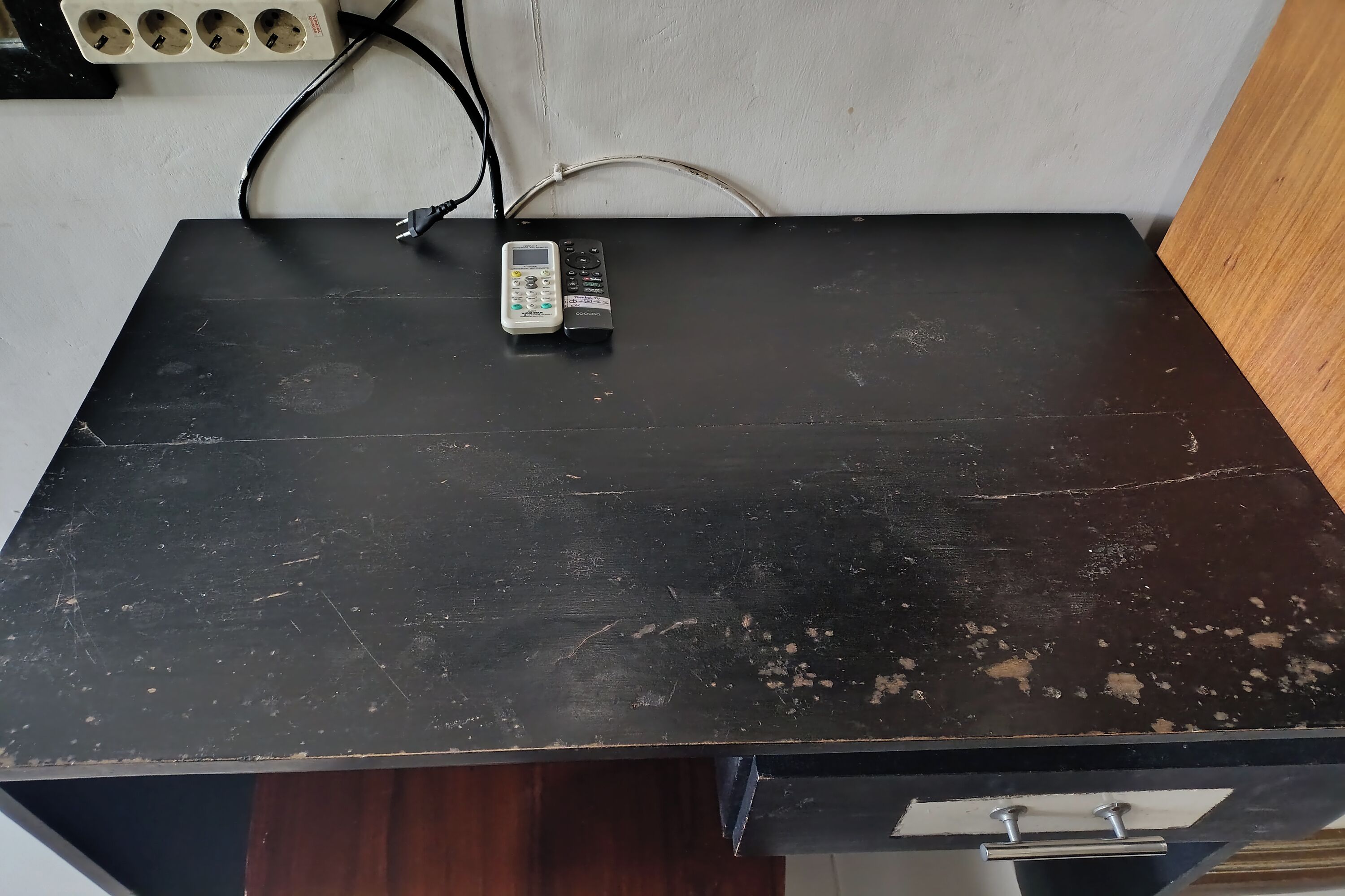 A black table with a remote control and a power strip.