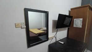 A small room with a bed, a mirror, a television, and a wooden cabinet. - Jj House Kost Exclusive Nologaten (Depok)