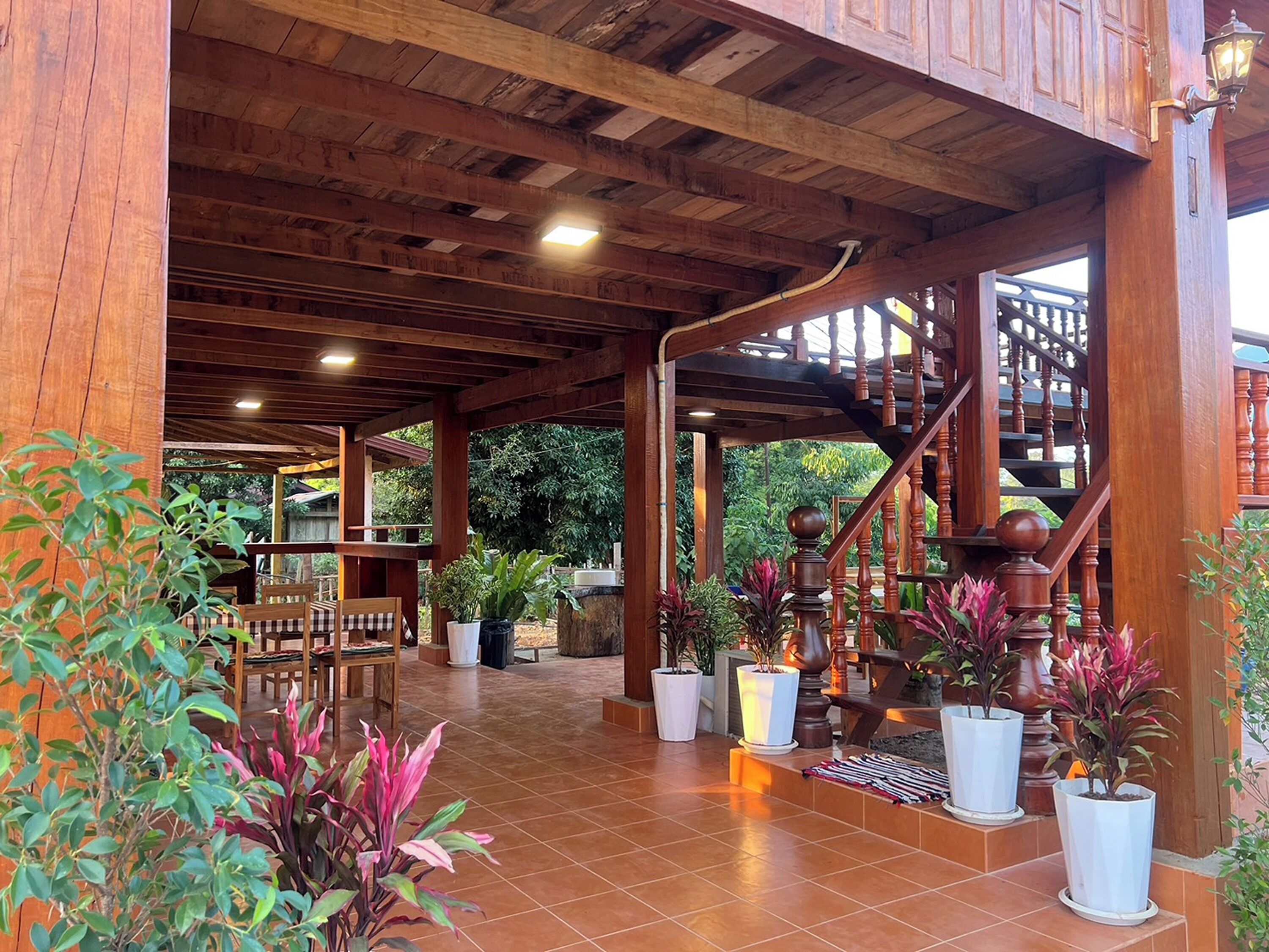 A covered outdoor area with wooden beams, a staircase, and potted plants.