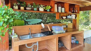 A compact kitchen with a wooden countertop, two sinks, and a variety of potted plants. - Vangnamthip Meung Feung Hotel (Ban Don)