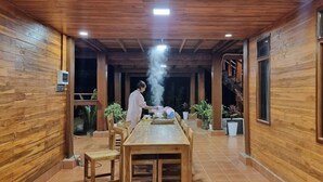 A wooden interior with a long dining table, chairs, and potted plants. - Vangnamthip Meung Feung Hotel (Ban Don)