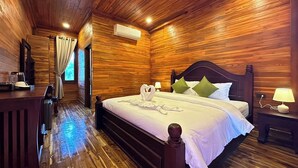 A wooden-paneled bedroom with a large bed, bedside lamps, and a desk with a chair. - Vangnamthip Meung Feung Hotel (Ban Don)