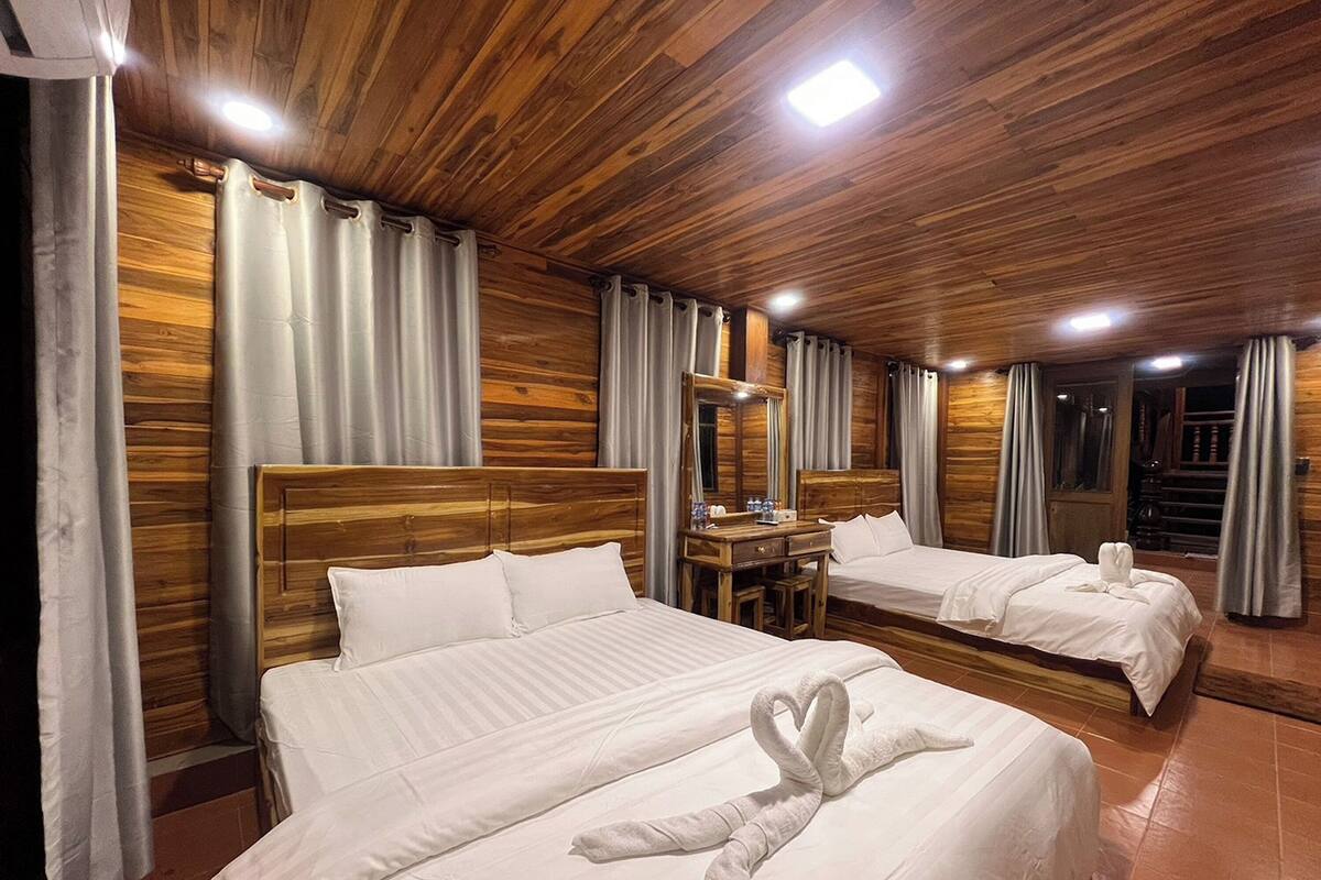 A hotel room with wooden paneling, two beds, a dresser, and a mirror.