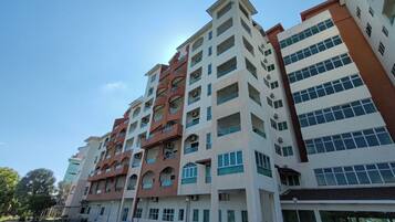 Un edificio residencial de varios pisos con balcones, piscina y césped cuidado.