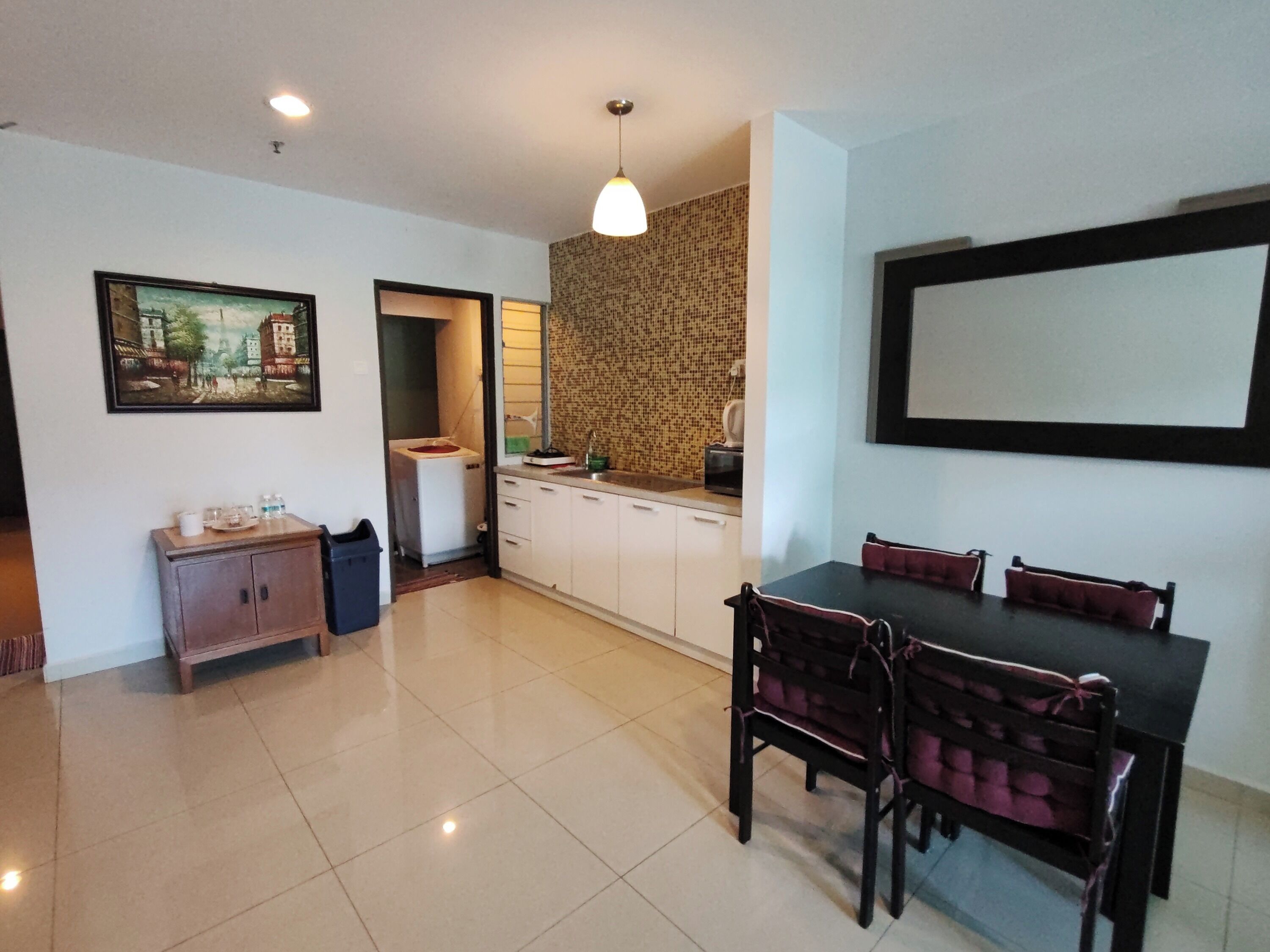 Un coin repas avec une table et des chaises, une cuisine avec un crédence décorée, et un tableau encadré au mur.
