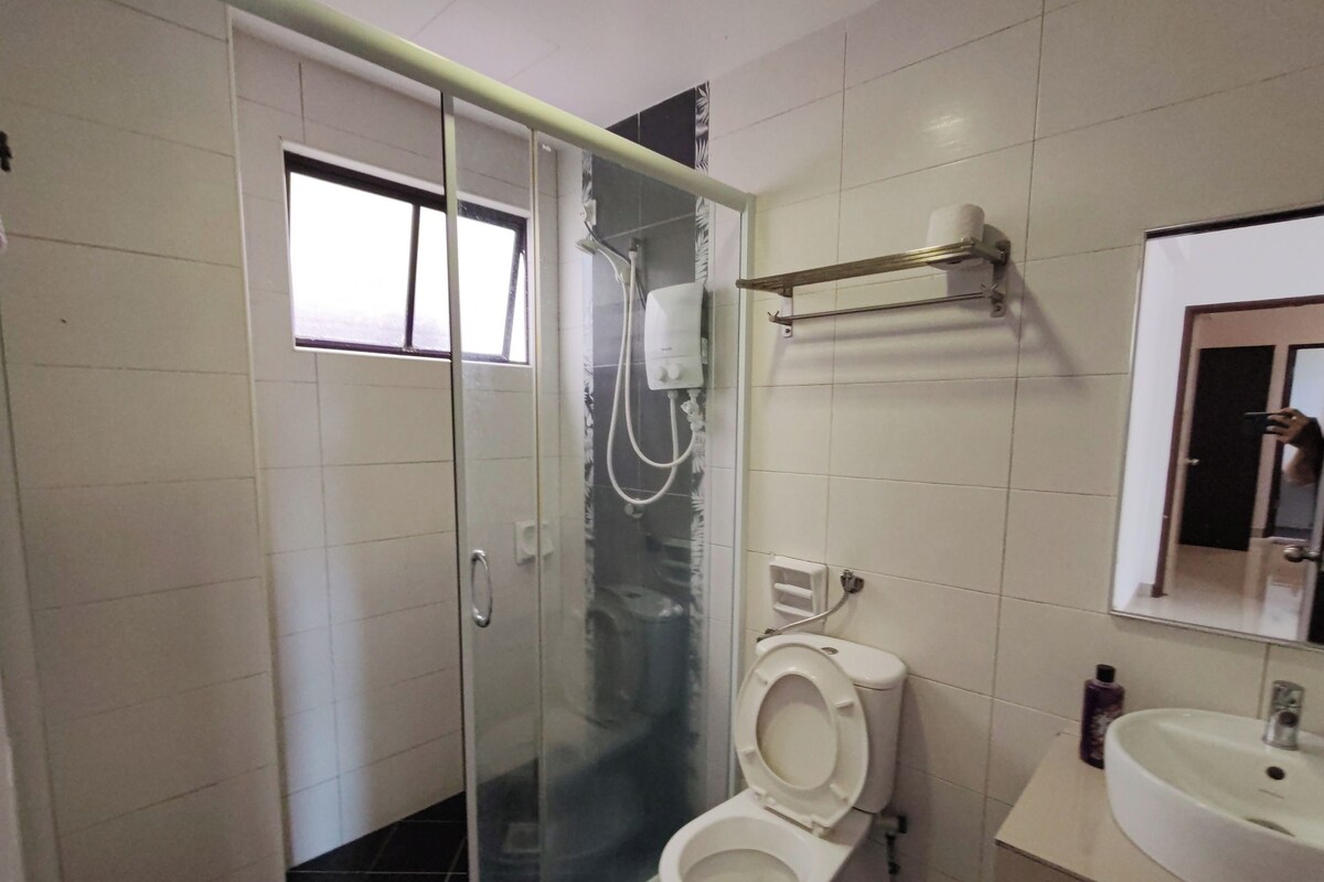 A bathroom with a glass-enclosed shower, a toilet, a sink, and a mirror.