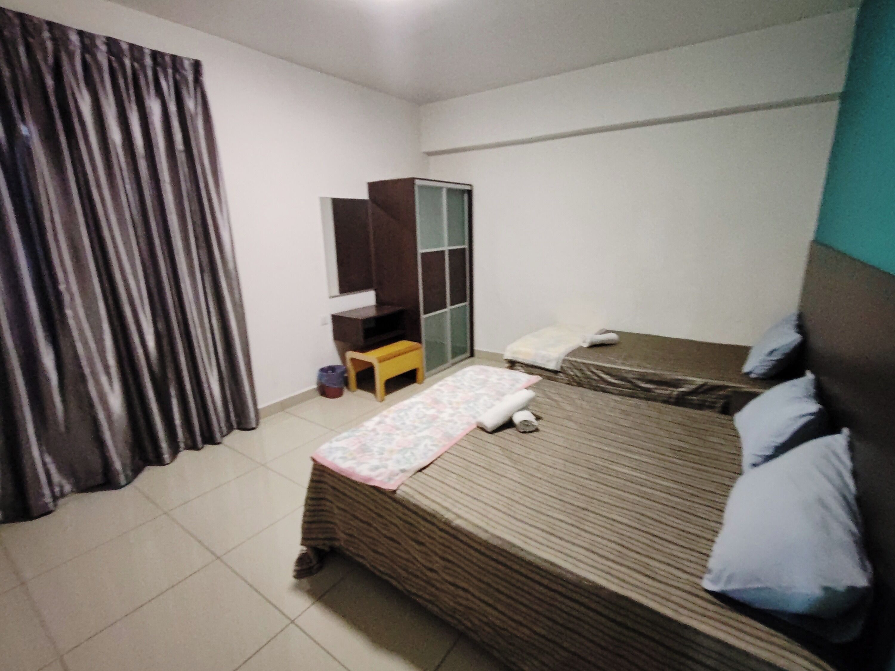 Un dormitorio con cama, una mesita, un armario y una cortina.