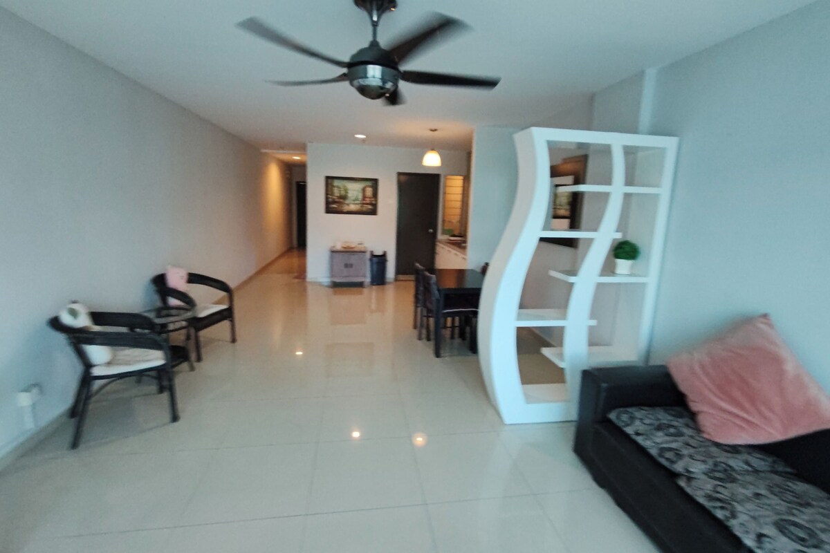 A modern living room with a ceiling fan, a sofa with a patterned cushion, and a white shelving unit.