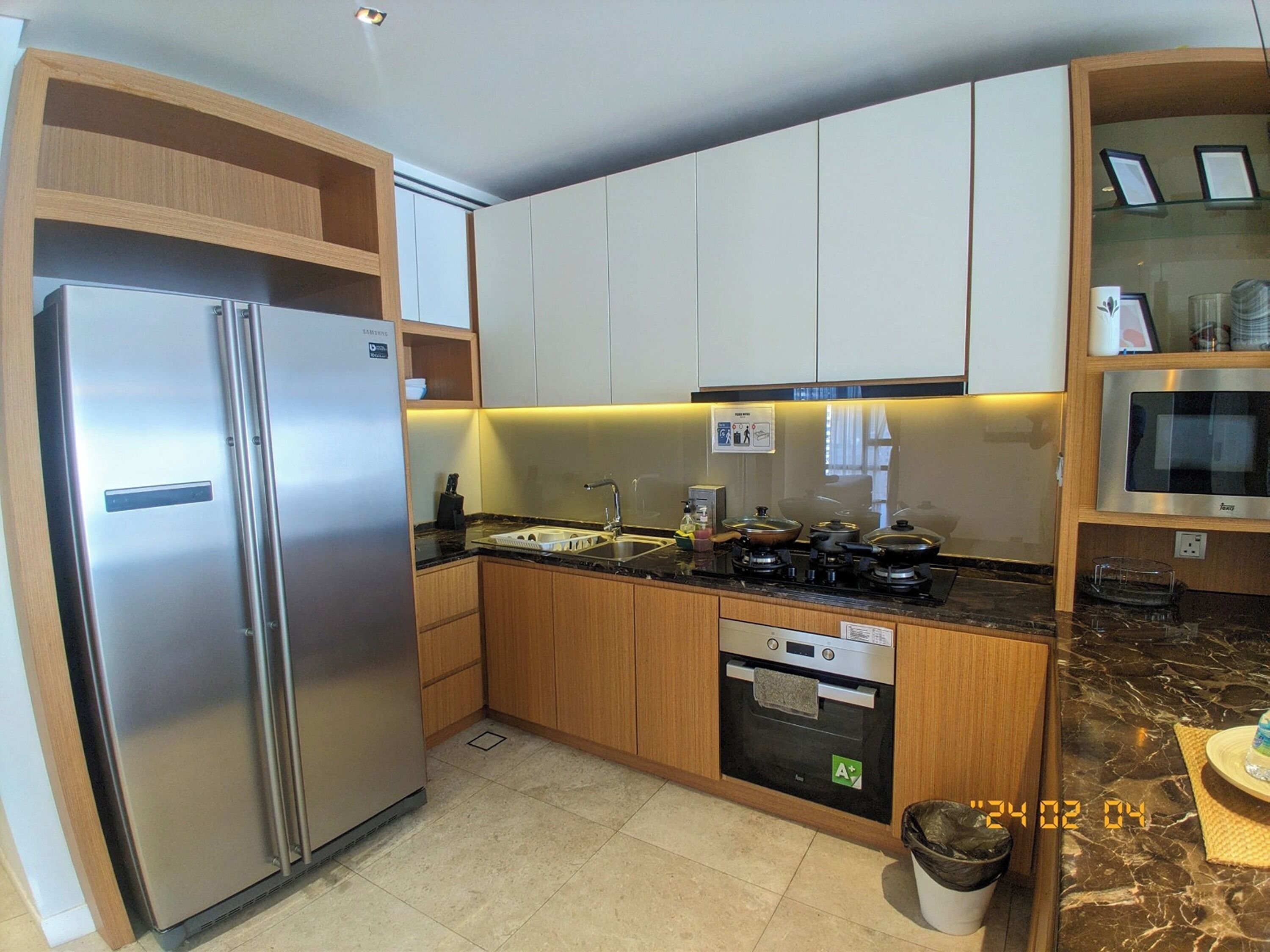 A modern kitchen with stainless steel appliances, wooden cabinets, and a marble countertop.