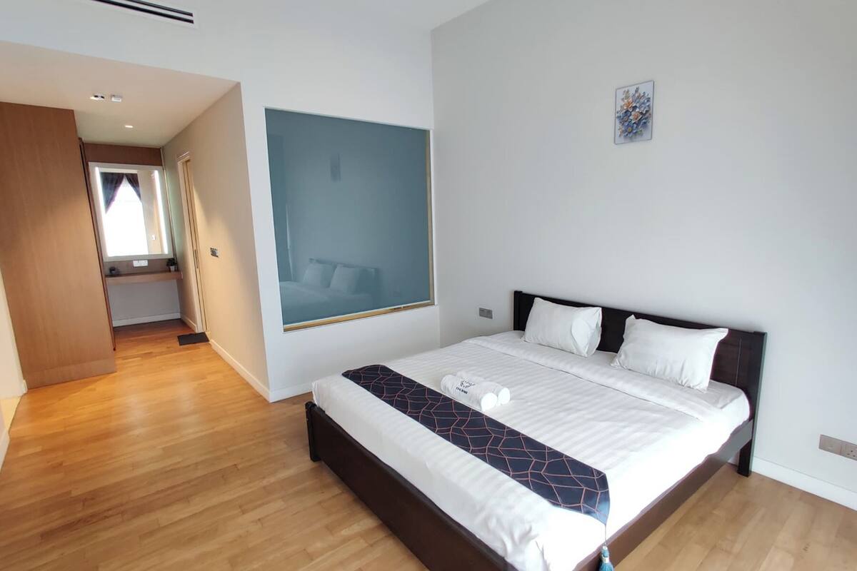Ein modernes Hotelzimmer mit einem großen Bett, Holzboden, einem großen Fenster und einer kleinen Küchenzeile.