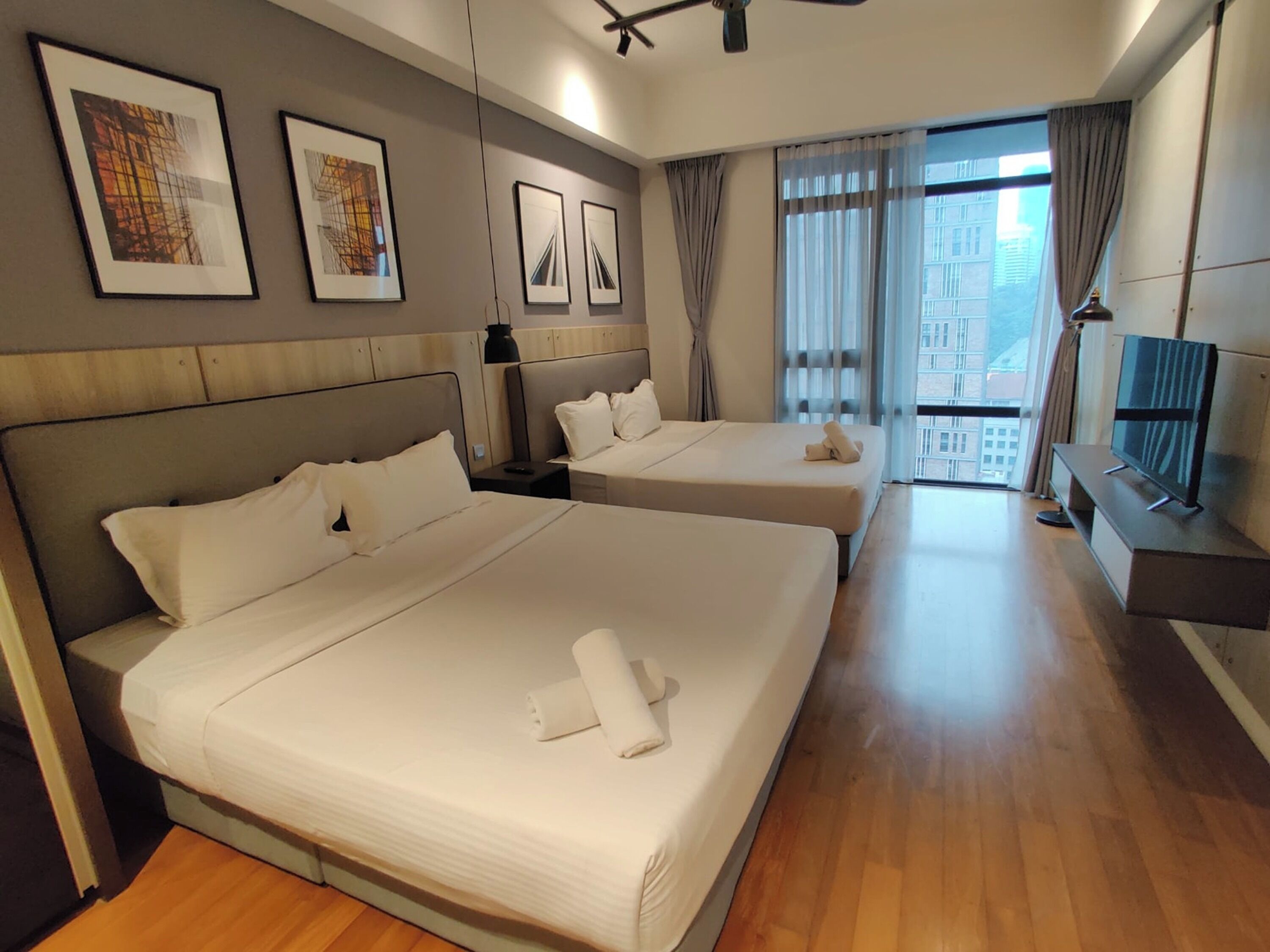 Habitación de hotel con dos camas, televisión y obras de arte en las paredes.