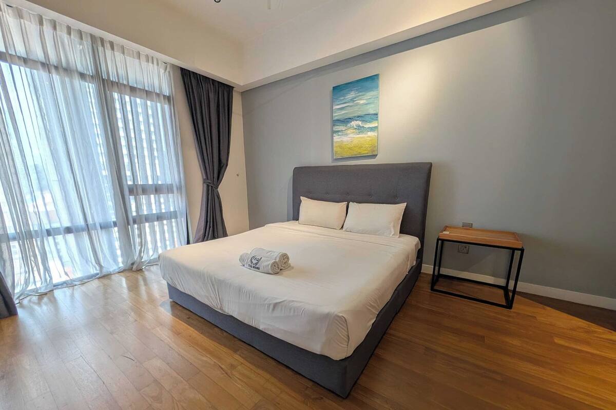 Ein modernes Hotelzimmer mit einem großen Bett, einem kleinen Nachttisch und einem Gemälde an der Wand.