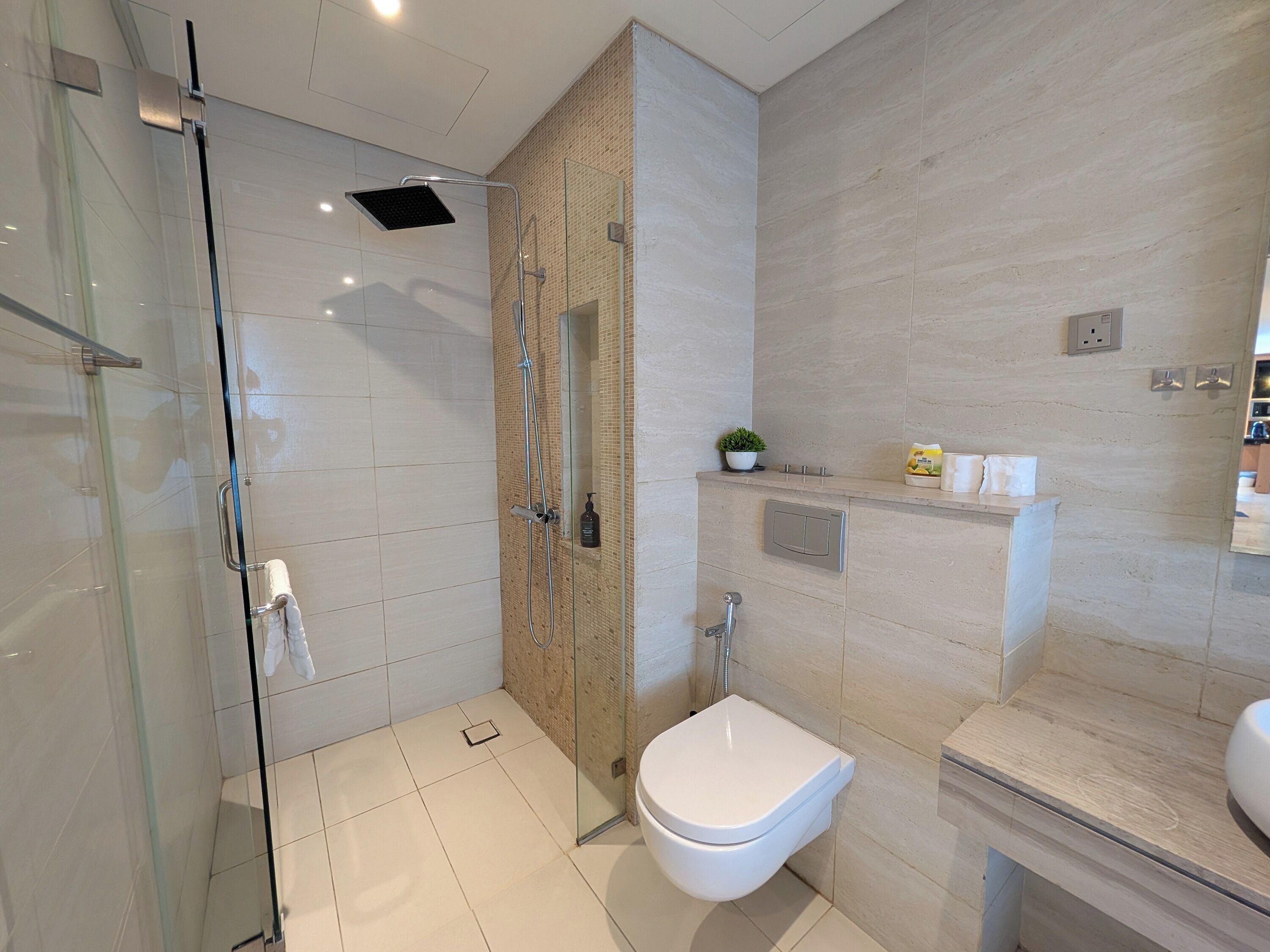 A modern bathroom with a glass-enclosed shower, a white toilet, and a vanity with a mirror.