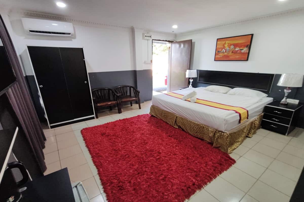 Une chambre d’hôtel avec un lit, un tapis rouge, un bureau, une chaise, une armoire et un tableau au mur.