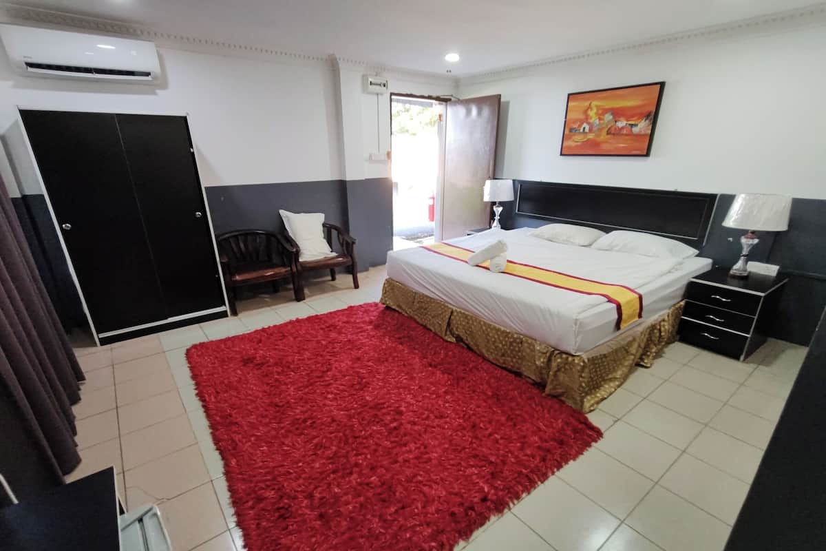 Une chambre à coucher avec un lit, un tapis rouge, une chaise, une table de chevet et un tableau accroché au mur.