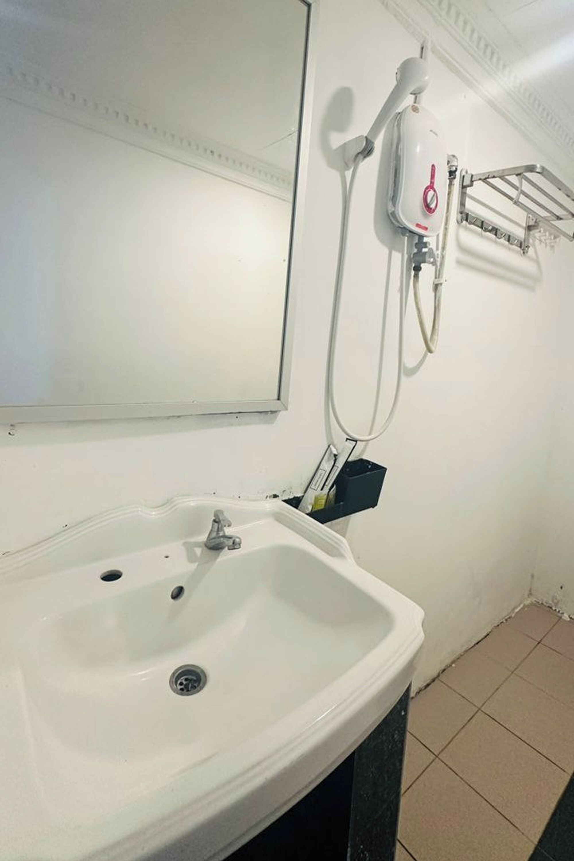 Une salle de bain avec un lavabo blanc, un miroir et une douche murale.