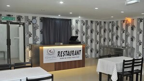 Un restaurante con mostrador de recepción, mesas y sillas.