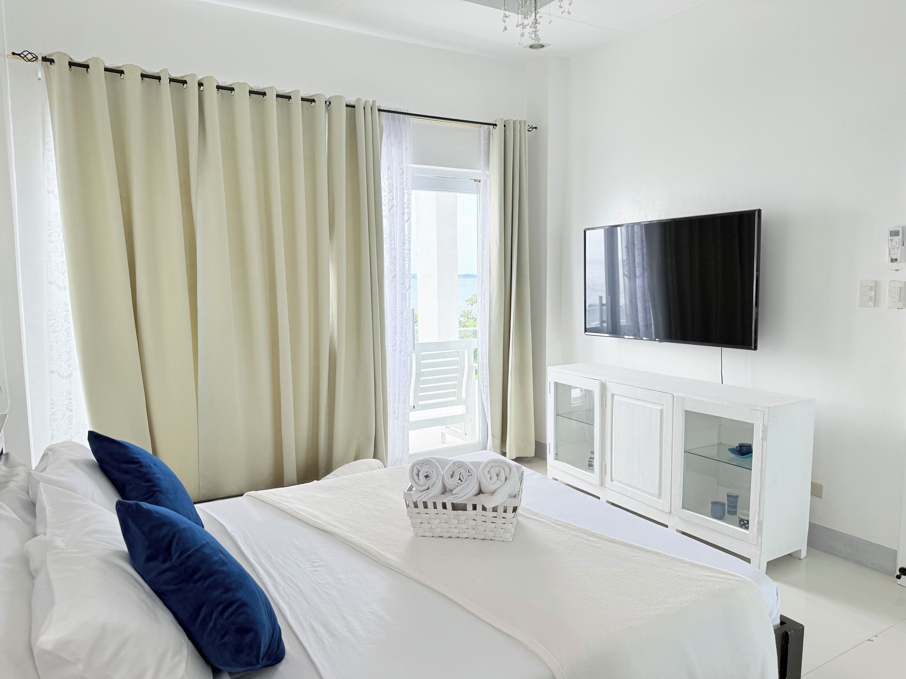 A hotel room with a bed, a television, a white cabinet, and a window with curtains.