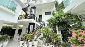A multi-level atrium with potted plants, a staircase, and a sign that reads "Welcome to the Hotel." - Chateau Du Soleil (San Fernando)