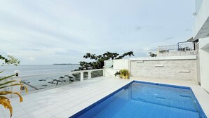 A rooftop swimming pool with a view of the sea, white tiled flooring, and potted plants. - Chateau Du Soleil (San Fernando)