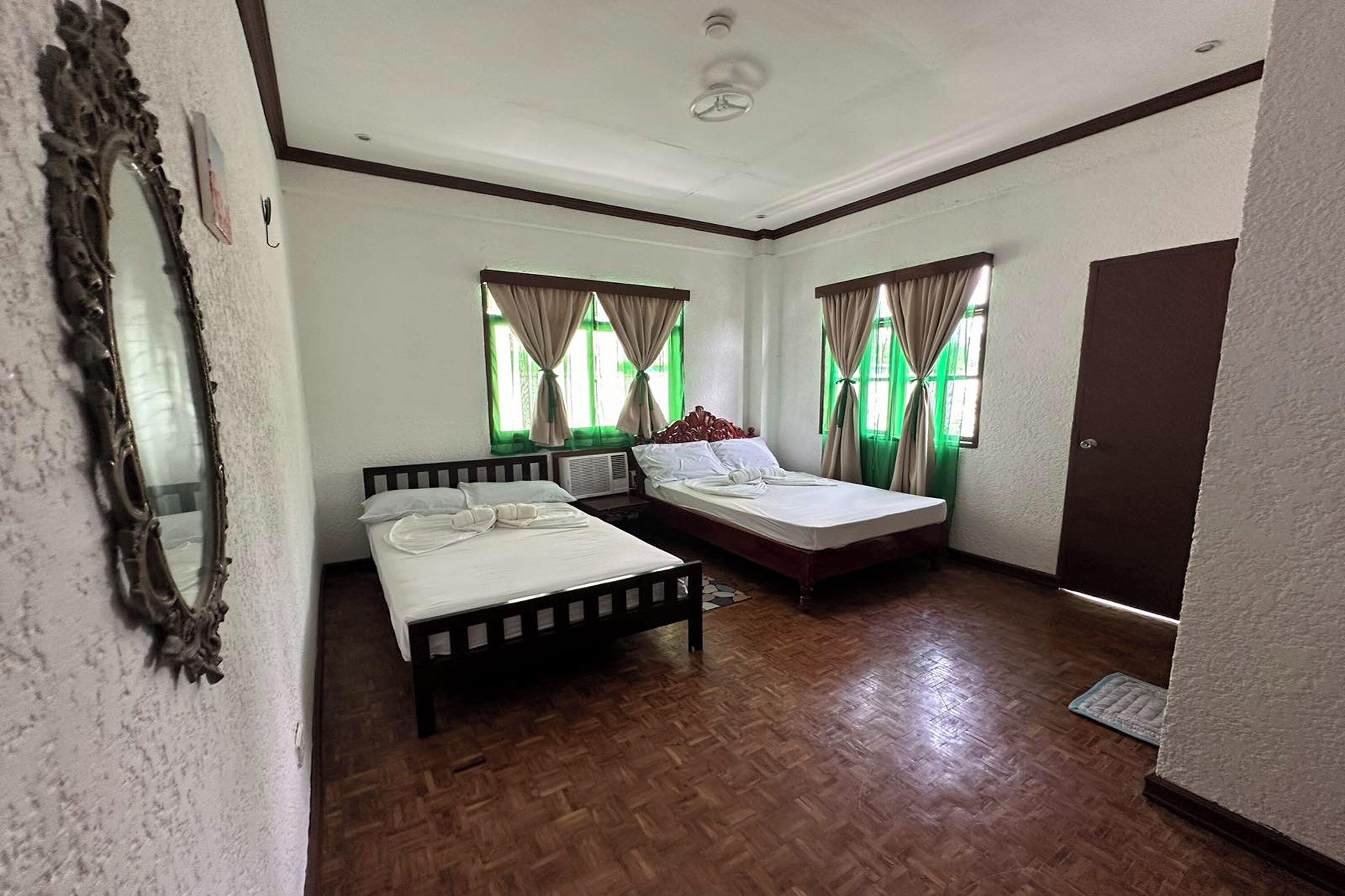 A room with two beds, a mirror, and a door.