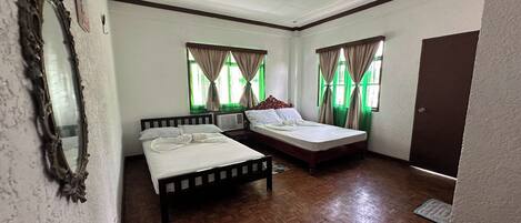 A room with two beds, a mirror, and a door.