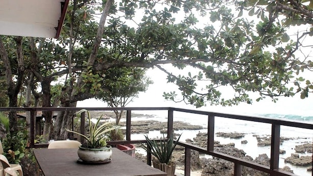 An outdoor seating area with a table and chairs, surrounded by potted plants, overlooking a rocky coastline. - Hardin De Corales (San Fernando)