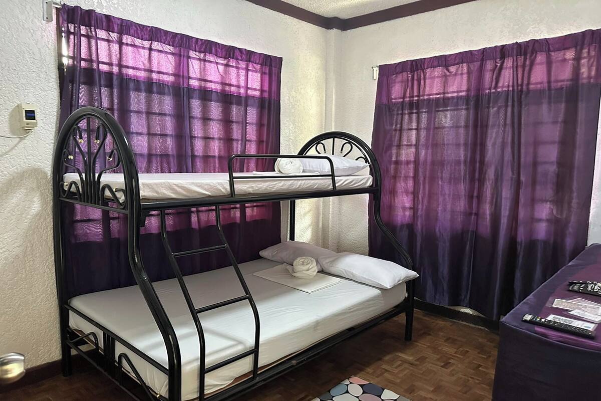 A bunk bed with a control panel, purple curtains, and a small table with items on it.
