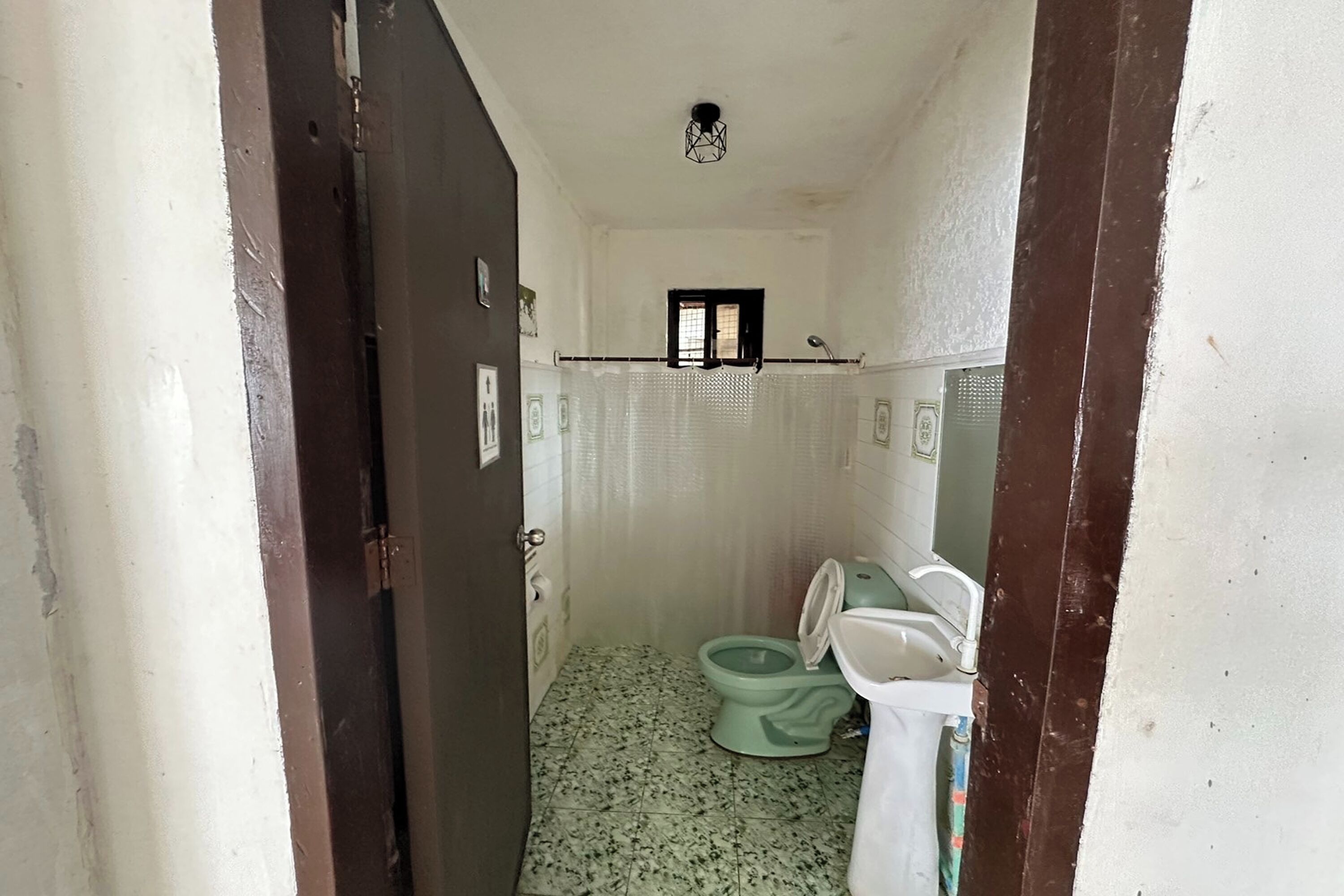 A small, narrow bathroom with a toilet, sink, and a window.