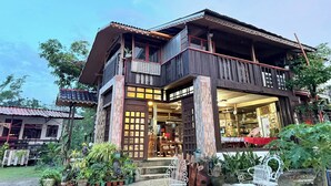 A two-story wooden house with a balcony, a shop on the ground floor, and a garden with potted plants. - Hardin De Corales (San Fernando)