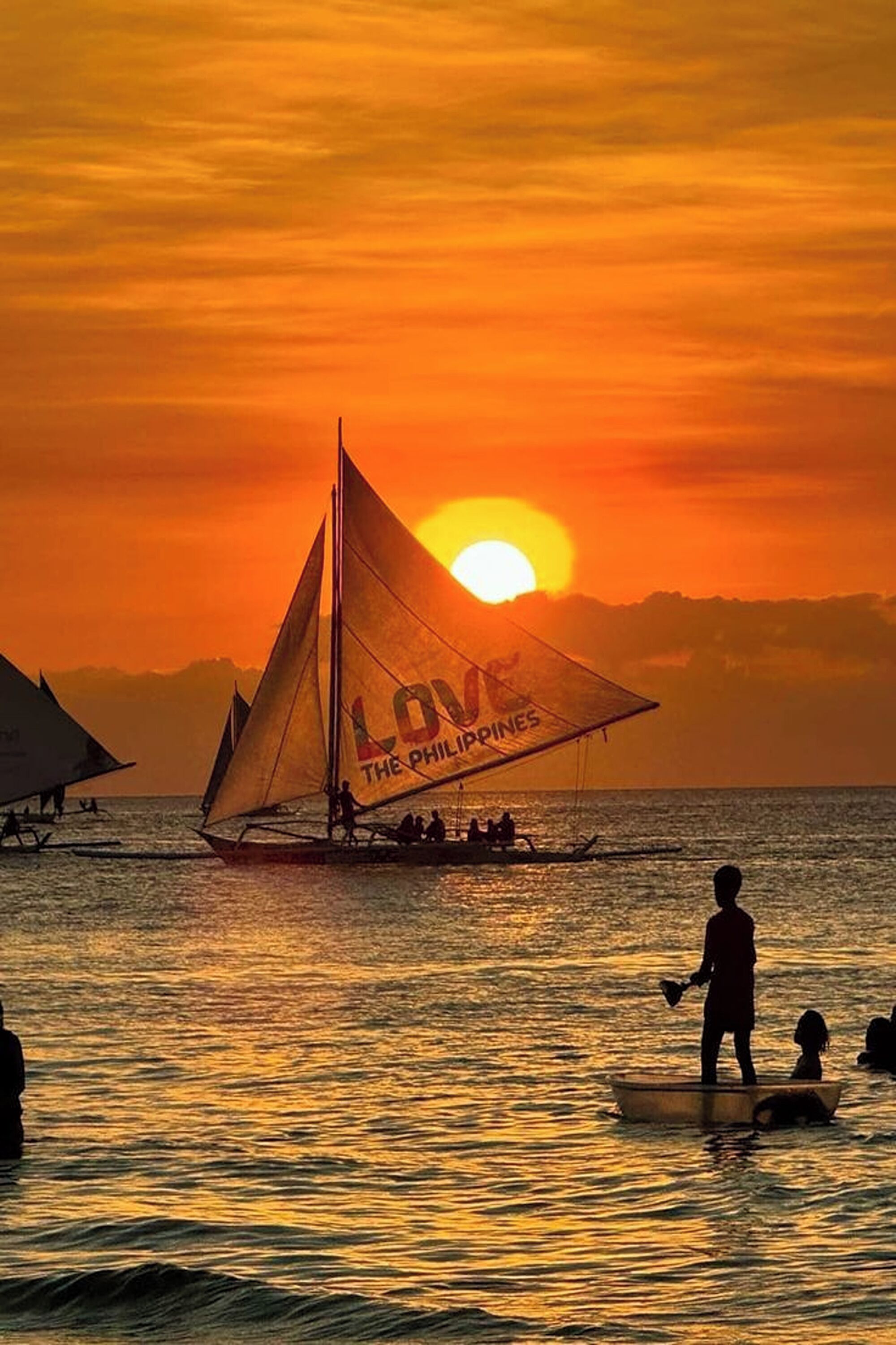 A sunset scene with a sailboat labeled "LOVE THE PHILIPPINES" on the water.