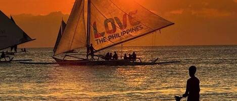 A sunset scene with a sailboat labeled "LOVE THE PHILIPPINES" on the water.