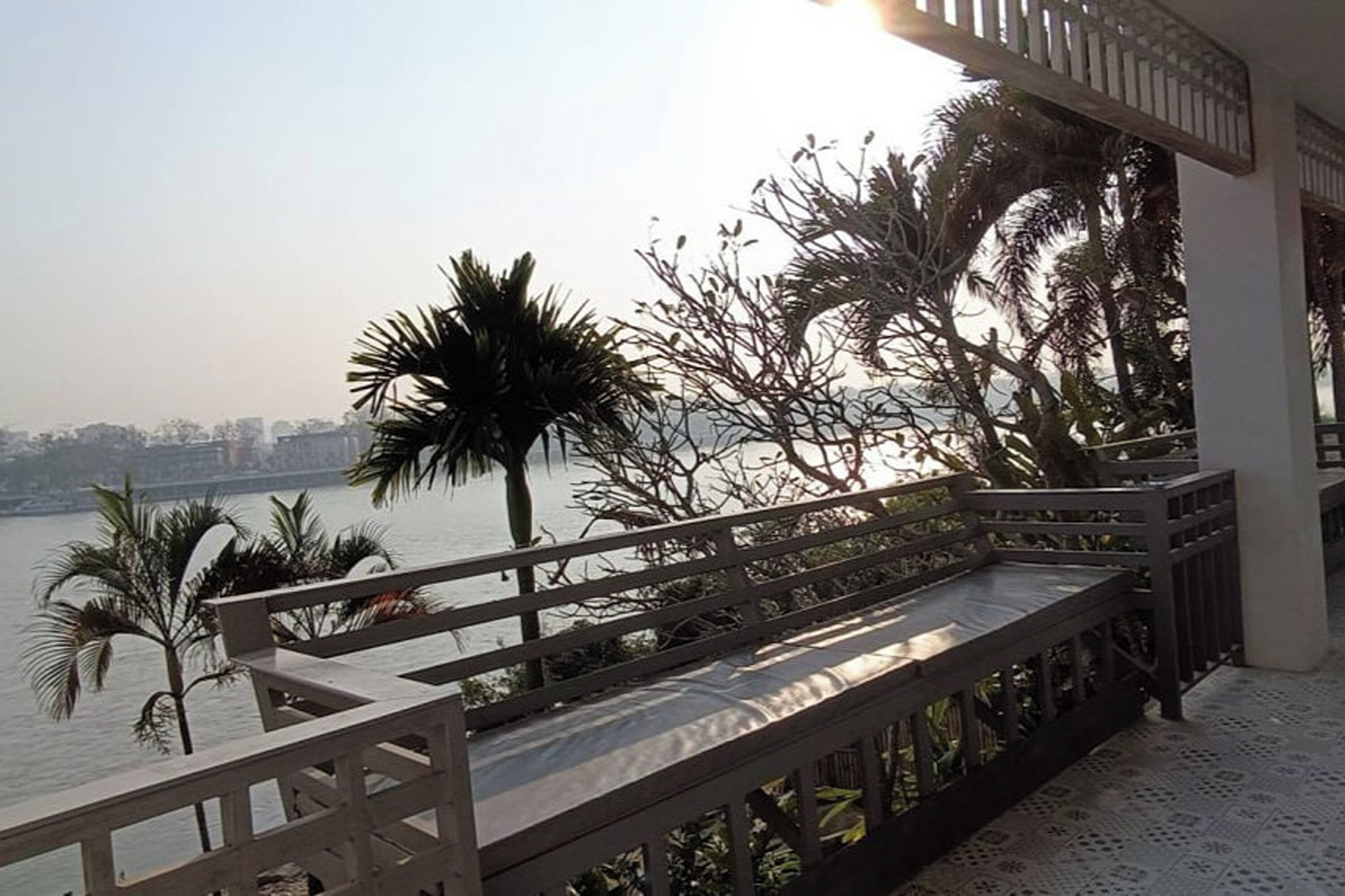 A balcony with a view of a river and palm trees.