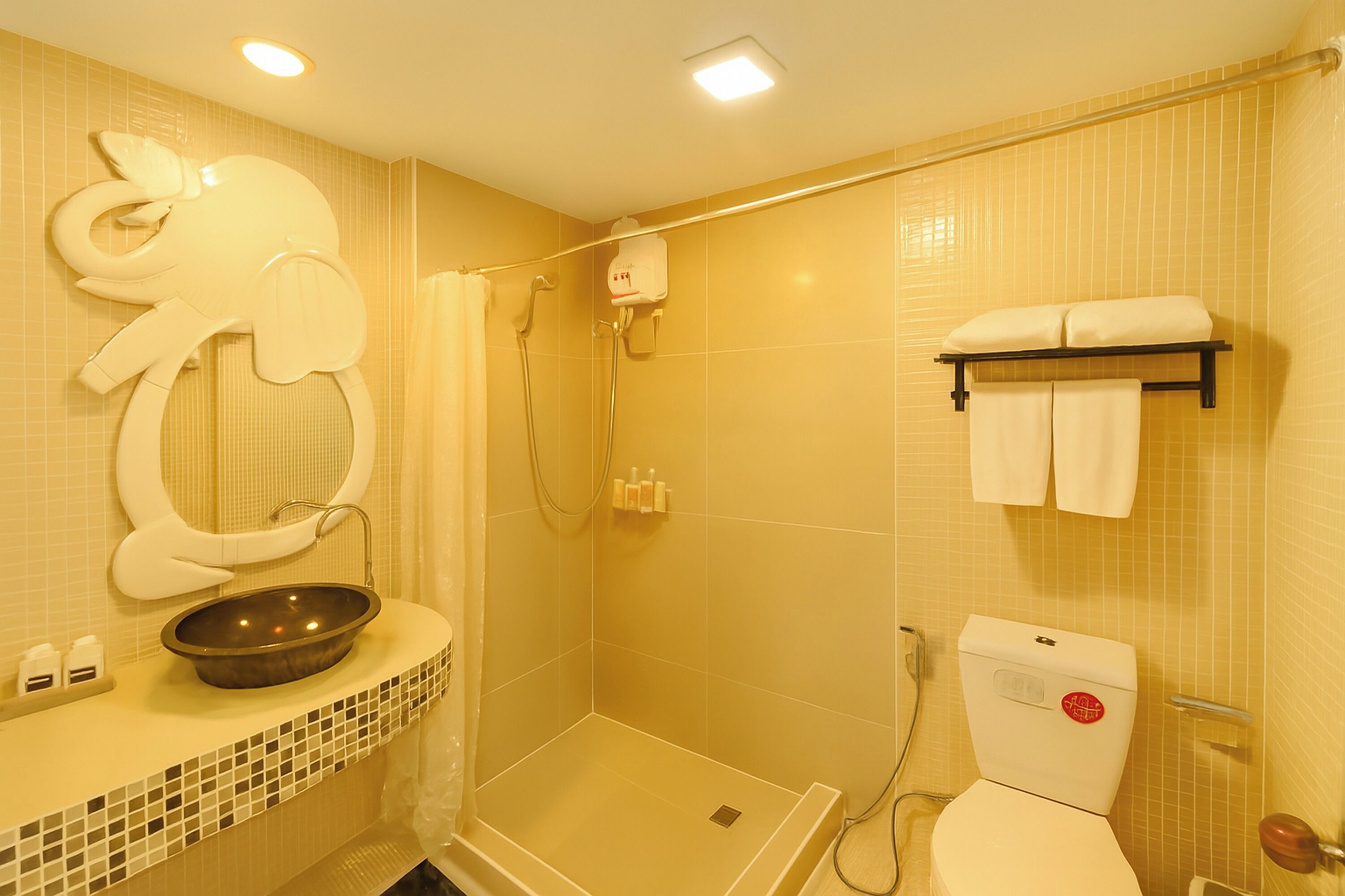 A bathroom with a shower, toilet, and a sink with a decorative elephant-shaped basin.