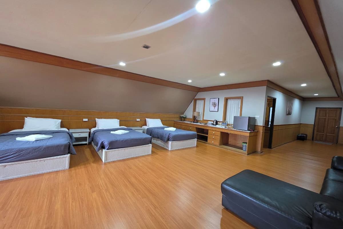 Una habitación amplia con tres camas, un escritorio y un sofá.