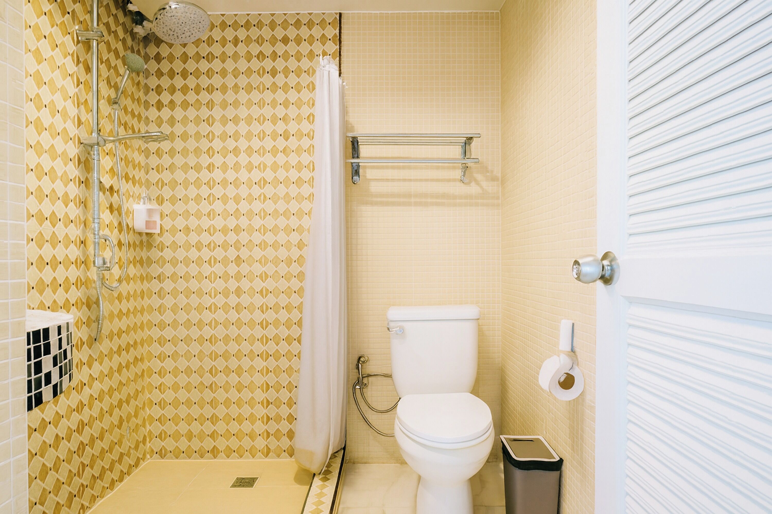 A bathroom with a shower, toilet, and a towel rack.