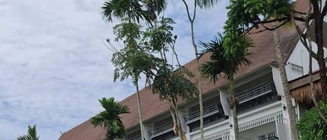 Un resort con area piscina, ombrelloni di paglia e un edificio a più piani con balconi.