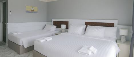 Habitación de hotel con dos camas, una mesita de noche con lámpara y un cuadro en la pared.