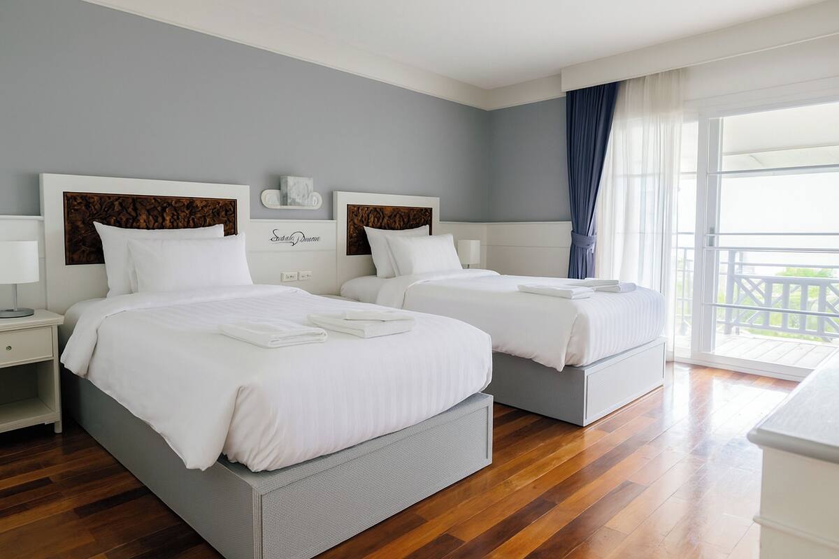 Habitación de hotel con dos camas, un balcón y vistas al exterior.