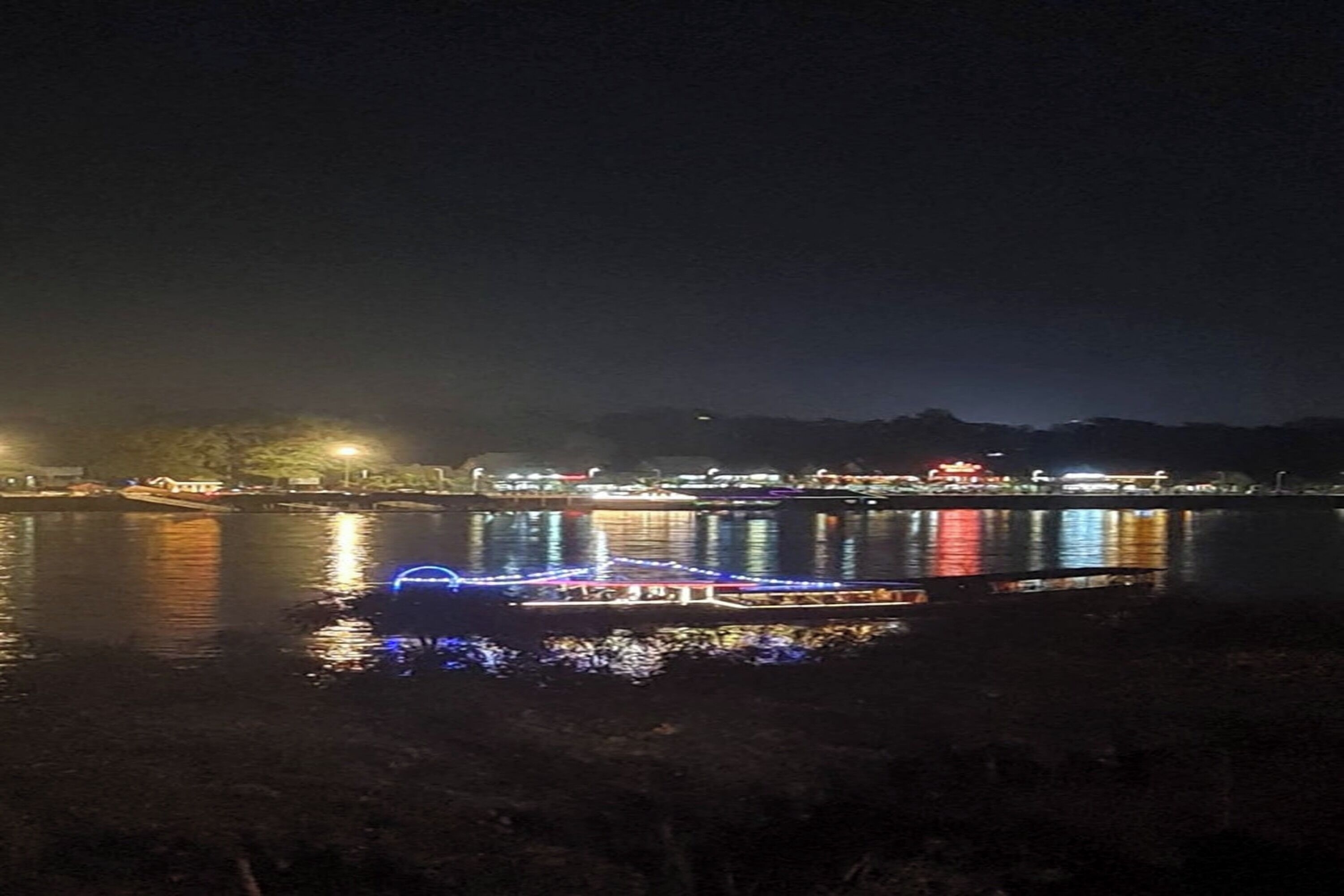 A boat with illuminated blue lights on a calm body of water at night.