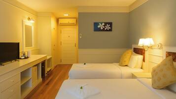 Habitación de hotel con dos camas, televisión, escritorio y lámpara de pared.