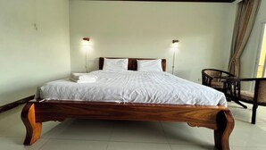 Una cama bien hecha con sábanas blancas, un cabecero de madera y dos lámparas de lectura fijadas a la pared.