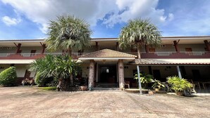 Un hotel con entrada techada, palmeras y cielo despejado.