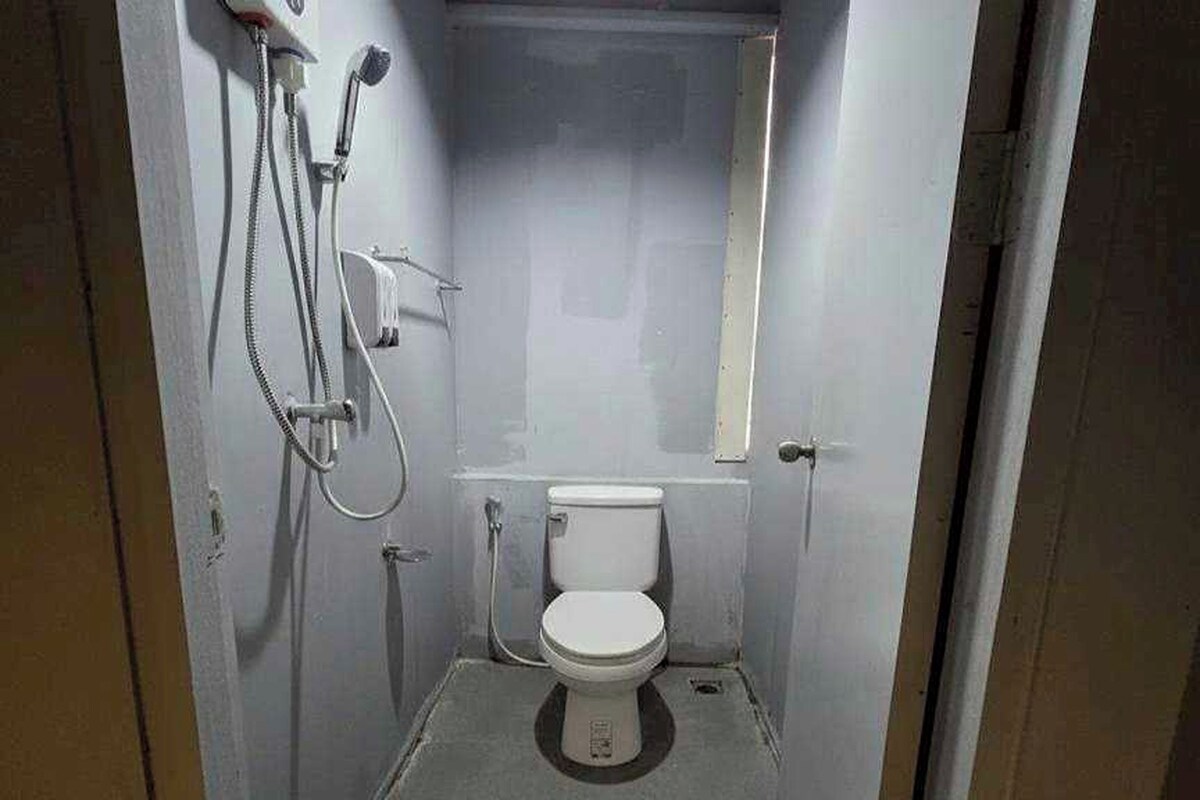 A small, compact bathroom with a toilet, a shower, and a sink.