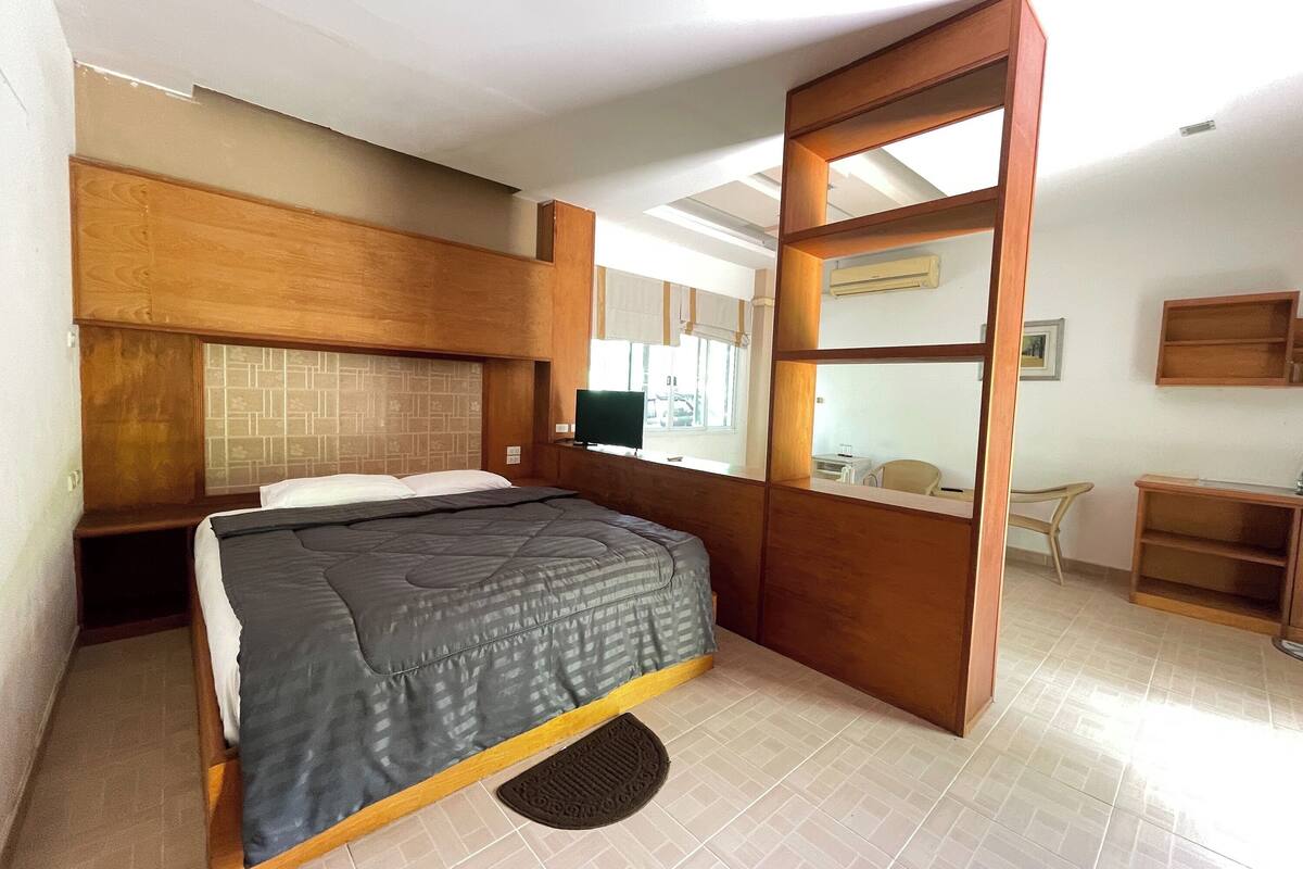Une chambre à coucher avec un lit, une tête de lit en bois, un bureau et une chaise.