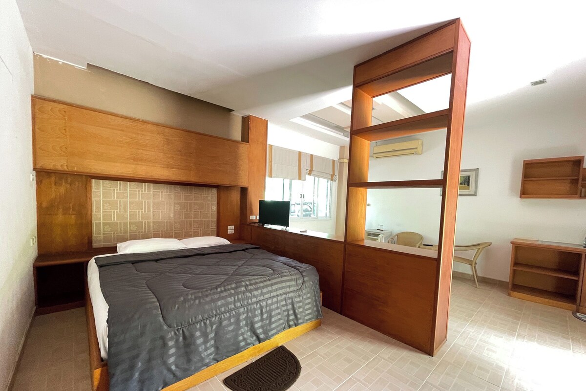 Un dormitorio con cama, cabecero de madera, escritorio y silla.