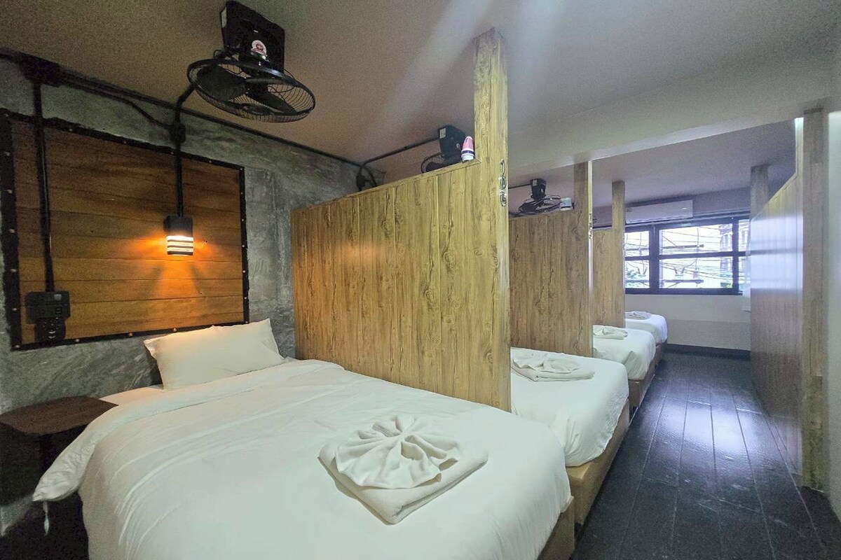 A hotel room with a wooden headboard, a bed with white linens, a bedside table, and a window with a view.