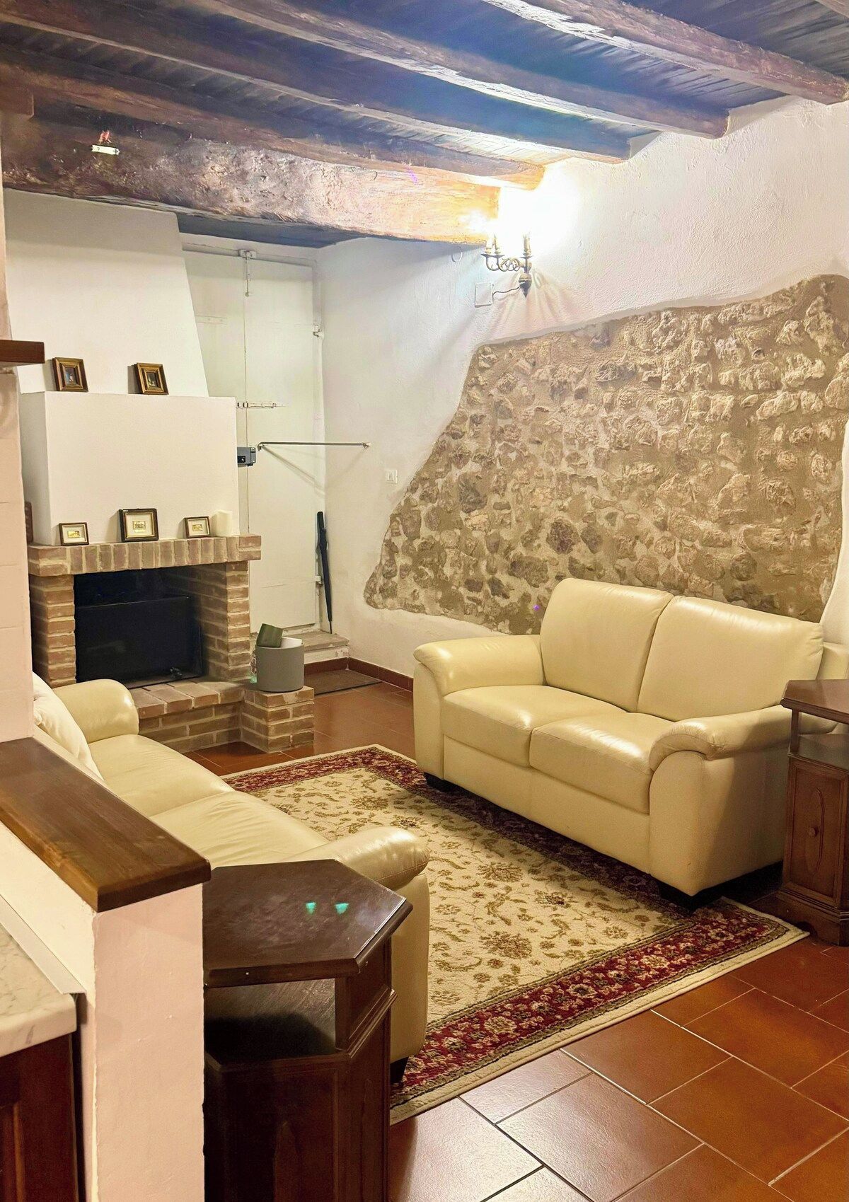 A living room with a stone wall, a fireplace, a sofa, and a television.